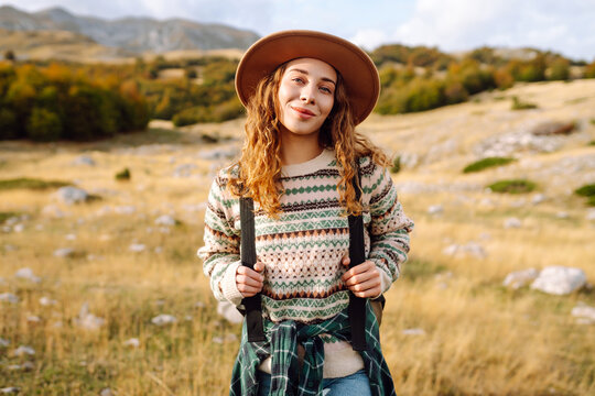 Young woman hiker with a briefcase on a mountain trail enjoying nature. Traveler on a hike and feeling freedom in the open air. Hiking, travel and nature concept. Active lifestyle.
