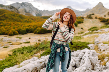 Young woman hiker with a briefcase on a mountain trail enjoying nature. Traveler on a hike and...