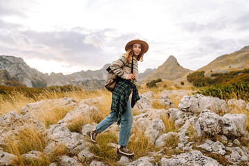 Young woman hiker with a briefcase on a mountain trail enjoying nature. Traveler on a hike and...