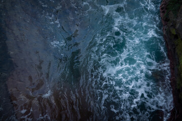 A breathtaking Aerial View showcasing the Turbulent Ocean Waves crashing against a Rocky Coastline