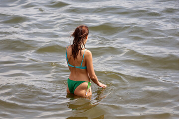 Young woman in bikini going to swim in water, beach vacation in summer