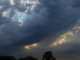 Beautiful yet ominous sunset before a summer storm, captured over open farmland with glowing sun,...