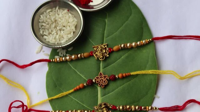 Traditional Rakhi arrangement with rice, roli, and sacred threads on a green leaf for Raksha Bandhan celebration