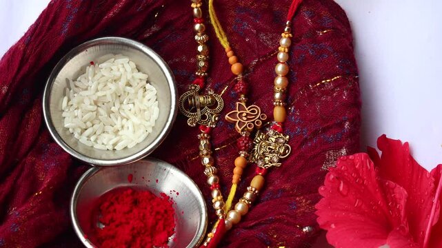 Rakhis with roli and rice in steel bowls arranged on a red traditional cloth for Raksha Bandhan celebration