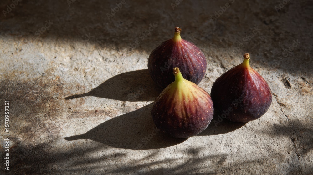Poster fresh figs arranged on a stone slab create shadows on a sunlit surface with one area left untouched