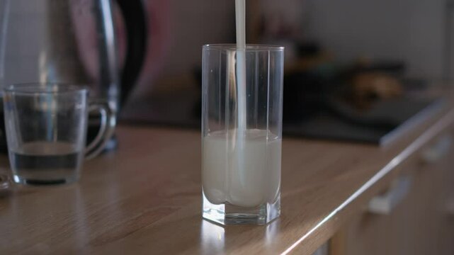 Pouring cold fresh kefir into a glass, close-up