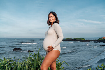 Confident pregnant woman standing near ocean, representing inner tech freedom and peaceful control...