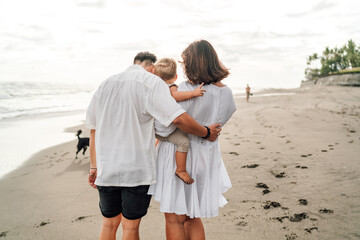 Family of three embraces, toddler pointing forward as symbol of guided discovery, reflecting design...