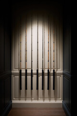 Fishing rods are neatly arranged vertically on a wooden wall panel in a dimly lit room. Concept: Fishing equipment display