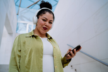 young woman with wireless headphones and a smartphone enjoys seamless digital interaction. Female...
