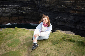 An Adventurous Woman Standing Gracefully at the Scenic Edge of Dramatic Cliffs with a View