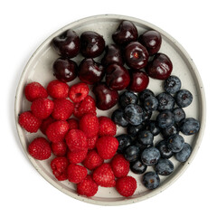 The High resolution fruit photo of mixed fruits including cherries, raspberries and blueberries arranged on a plate, taken with split focus technique.