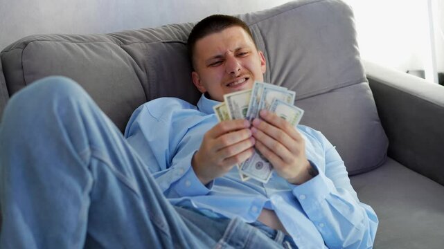 Happy guy holding cash in his hands with a smile on his face.
A joyful and happy man, happy that he earned a lot of money.
Success and wealth.
Cash in man's hands