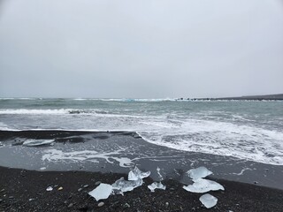 Glacial Ice Fragments on Black Volcanic Beach in Iceland on a Gloomy Day