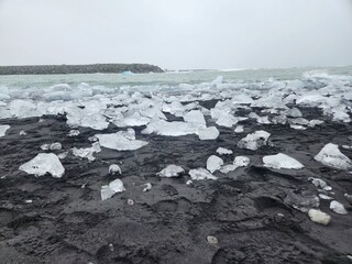 Glacial Ice Fragments on Black Volcanic Beach in Iceland on a Gloomy Day