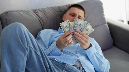 A gambling man wins money in a game and is happy while sitting on the couch.
Happy gambler with money in his hands.
Sports or casino betting.
Easy money and excitement