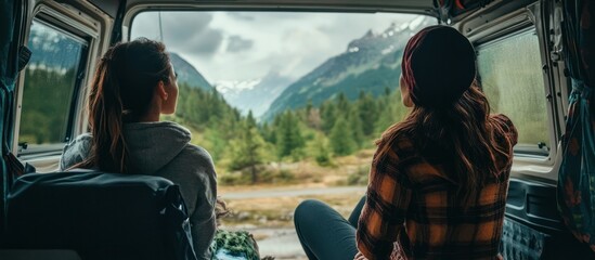 Two women inside a van, gazing at a mountain landscape
