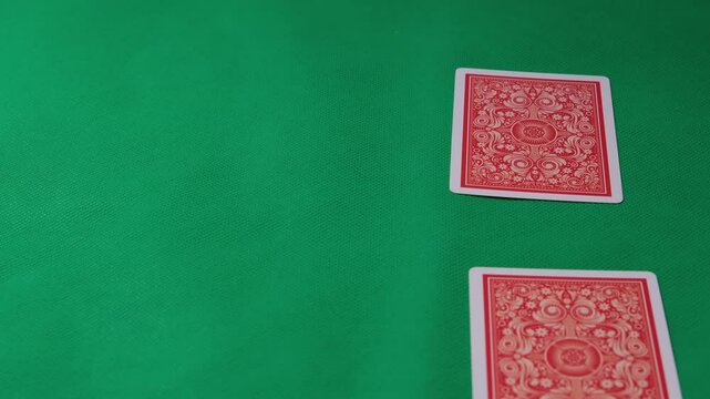Close-up of hand dealing playing cards on vibrant green felt poker table in a casual indoor setting