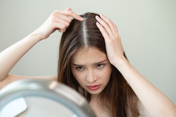 problem hair fall asian young woman, girl worry about balding, looking at scalp in mirror, hand in...