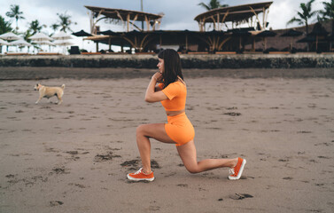 Fit brunette woman performing lunge with intense focus, combining body sculpting with minimalist...