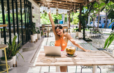 Young woman stretches with laptop after remote task completion, illustrating balance between...