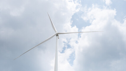Striking image of a wind turbine perfectly centered beneath a vivid blue sky with scattered clouds....