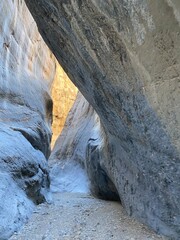 Exploring the narrow canyon surrounded by towering rock formations at golden hour in a remote location