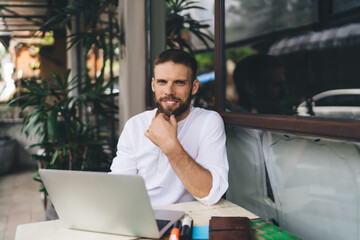 Portrait of smiling freelancer at laptop, hand on chin, exuding trust and calm. Symbol of...