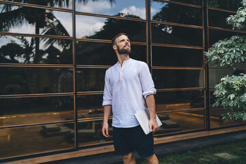 Freelancer outdoors holding laptop and looking upward with ambition, expressing determination and...