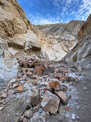 Rockslide reveals geological formations in a rugged canyon during midday sun in a remote location