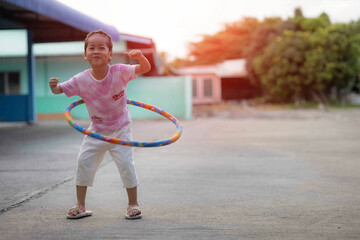 A girl is having fun playing hula hoop in a rented house. She smiles happily.