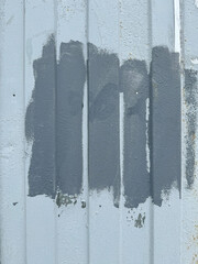 Gray paint patches on corrugated metal wall