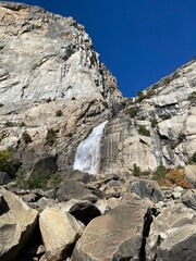 Majestic waterfall cascading down rugged cliffs in a sunny landscape during autumn in the mountains