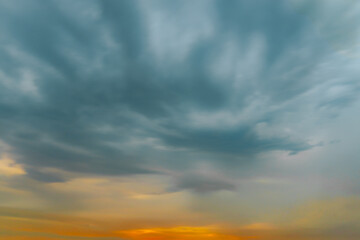 Thick, dark storm clouds swirl and stretch across the sky in a dramatic display, creating a moody...