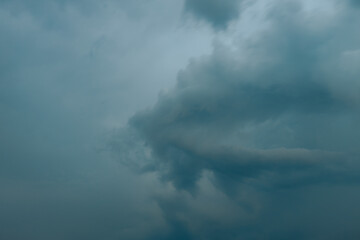 Thick, dark storm clouds swirl and stretch across the sky in a dramatic display, creating a moody...