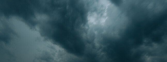Thick, dark storm clouds swirl and stretch across the sky in a dramatic display, creating a moody...