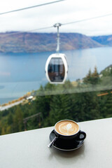 A cup of coffee with views of Skyline Queenstown Gondola, Lake Wakatipu, and mountains from...