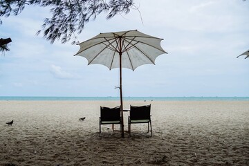 Camping chair under beach umbrella on the beach, enjoying a perfect summer day in Thailand. Holiday concept.