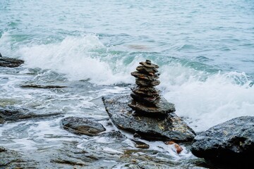 Pebble heap on a beach serene blue sea background zen balanced stones. Close up of rock stack beach in Thailand. Balanced stones on a pebble beach. Nature background concept of balanced rock tower