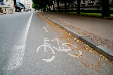 Empty urban street with marked bicycle lane and white bike symbol leading forward alongside...