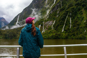 adventurous girl admires numerous waterfalls cascading down a mountain cliff during heavy rainfall,...