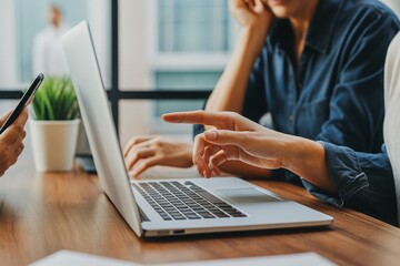 Close up depicts teamwork with a laptop, pointing, and mobile device in an office environment fostering collaboration and strategic planning together seamlessly