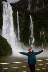 woman spread her arms next to powerful Stirling Falls falling from high dramatic mountain cliff...
