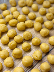Raw dough balls for baking traditional walnut-shaped cookies with condensed milk filling, close-up on wooden table