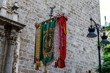 Clergymen march with flags during Corpus Christi in Spain against the backdrop of a church wall and...