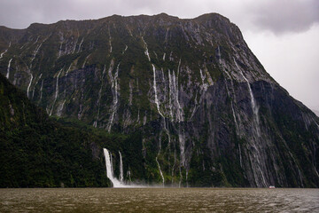 powerful Stirling Falls cascade from dramatic mountain cliffs during heavy rainfall, scenic ferry...