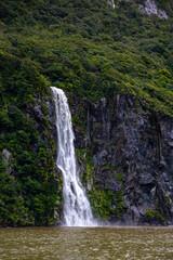 Fototapeta premium beautiful Bridal Veil Falls falling from dramatic mountain cliffs during heavy rainfall, scenic ferry cruise through Milford Sound, Fiordland National Park, Southland Region, South Island, New Zealand