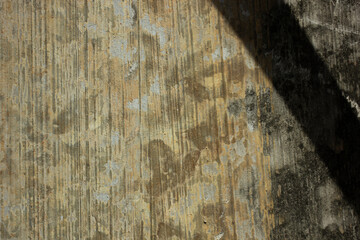 Close-up of a weathered concrete wall texture with vertical water streaks and peeling paint. An...