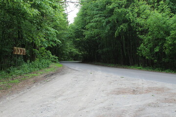 Exit from a dirt road onto a forest asphalt road, at the exit there is an old sign indicating the...