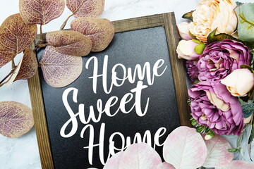 Home Sweet Home text on blackboard with flowers decoration on marble background
